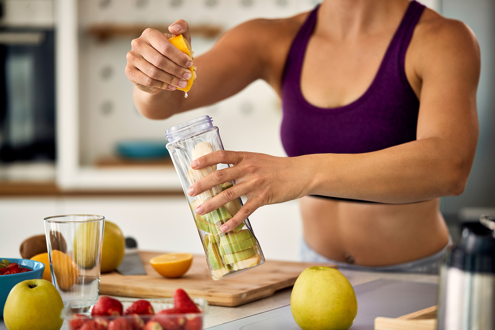 mladá fit žena vymačkáva citrón do smoothie